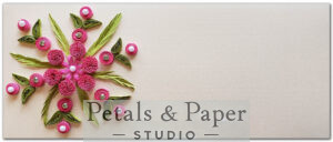 Handcrafted envelope with pink quilled flowers, green leaves, and pearl accents on a beige textured background, ideal for gifting, weddings, and invitations.