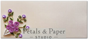 Handcrafted envelope featuring a quilled purple floral bouquet with green leaves and pearl accents on a beige textured background, ideal for weddings, gifting, and invitations.