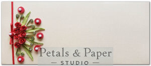 Handcrafted envelope featuring red quilled roses, green leaves, pearl accents, gemstones, and a satin ribbon on a beige textured background, perfect for gifting and invitations.