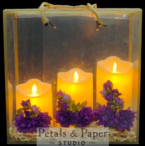 Set of three LED candles (4, 5, and 6 inches) in a transparent plastic box bag with purple foam flowers and greenery, perfect for Valentine's Day, home décor, or gifting occasions.