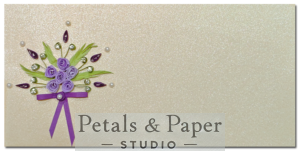 Handcrafted greeting card with lavender quilled roses, green leaves, pearl embellishments, and a purple ribbon bow on a glittery background for gifting occasions.