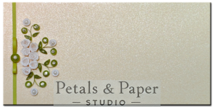 Handcrafted 7 x 3.5-inch pearl-finish envelope with white quilled roses, green vines, pearl embellishments, and a green ribbon clasp, perfect for weddings and special occasions.