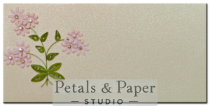 Handcrafted 7 x 3.5-inch pearl-finish envelope with soft pink quilled flowers, rhinestone accents, and green leaves, ideal for weddings, gift cards, and special occasions.