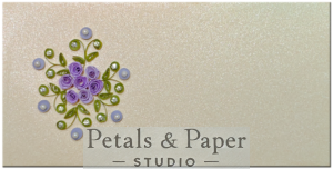 Handcrafted decorative envelope with quilled purple roses, green leaves, pearl accents, and rhinestones on a shimmering ivory background, perfect for gifting on weddings, birthdays, and special occasions.