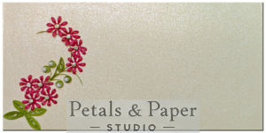 Handcrafted envelope with pink quilled flowers, green leaves, pearls, and rhinestones on a shimmering ivory background, perfect for weddings, anniversaries, and special gifting occasions.