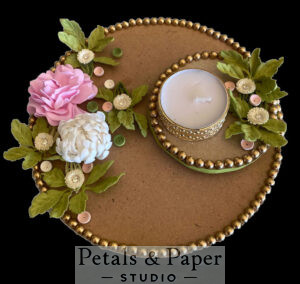 Handcrafted tea light holder plate with pink and white floral decorations, green leaf accents, and gold bead edging, featuring a gold-rimmed candle holder for festive and wedding décor.