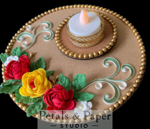 Handcrafted tea light holder plate with red and yellow flowers, green leaves, white accents, gold bead edging, and a gold-rimmed LED candle for festive and wedding décor.