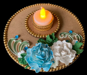Handcrafted tea light holder plate with blue and white roses, green leaves, quilled designs, pearl accents, gold bead edging, and an LED candle in a gold holder for festive décor.