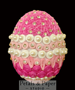 Handcrafted decorative egg featuring intricate pink and white quilled floral designs, embellished with pearls and sparkling gems, ideal as a centerpiece or gift for special occasions.