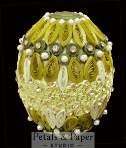 Handcrafted green and white decorative egg with intricate quilled teardrop designs, accented with pearls and sparkling gems, perfect for gifting, festive décor, or special celebrations.
