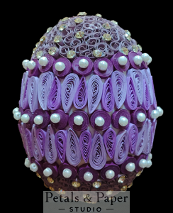 Purple decorative egg with intricate quilling patterns, pearl accents, and rhinestones, perfect for elegant home decor or festive displays.