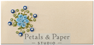 Handcrafted cream quilling card with blue roses, green leaves, sparkling crystals, and blue pearl accents for thoughtful messages.