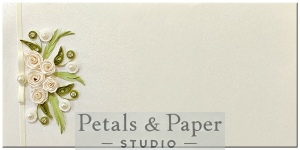 Handcrafted envelope with white quilled roses, green leaf motifs, and pearl embellishments on premium cardstock, perfect for weddings and special occasions.