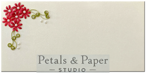 Handmade envelope with red quilled flowers, green leaves, and pearl embellishments, designed for weddings, festive gifting, and celebrations.