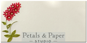 Handmade envelope with red quilled flowers and green leaves on a shimmering white background, ideal for weddings, birthdays, and festive gifting.