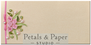 Handmade envelope featuring pink quilled roses, green leaves, pearls, and a pink ribbon on a beige textured background, ideal for weddings, anniversaries, and special gifts.