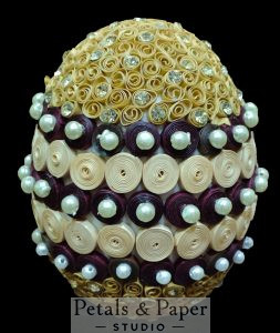 Handmade gold and maroon decorative egg with intricate quilling, pearl embellishments, and rhinestone details, perfect for home décor and gifting.