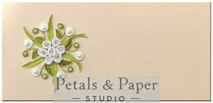 Handcrafted beige gift envelope with white quilled roses, green leaves, pearls, and rhinestone accents, perfect for weddings, festive gifting, and special celebrations.