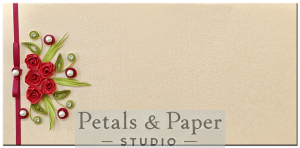 Handcrafted beige gift envelope with red quilled roses, green leaves, pearls, rhinestones, and a red satin ribbon, perfect for weddings, anniversaries, and festive gifting.