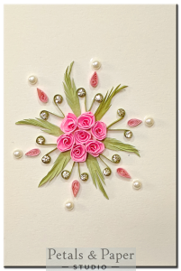 Handmade pink quilled rose greeting card with green leaves, rhinestones, pearls, and pink teardrop coils on cream background – perfect for birthdays and special occasions.