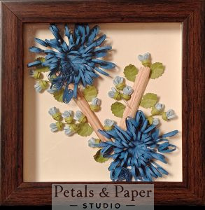 Handcrafted wooden decorative box with quilled blue chrysanthemum flowers, light blue buds, and green leaves under transparent lid – jewelry and keepsake storage