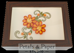 Handcrafted wooden jewelry box with orange and yellow quilled paper flowers, green vines, and glass cover design