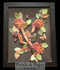 Handcrafted floral branch shadow box frame with coral and pink paper flowers, textured leaves, and wooden branch design in black frame for elegant home wall décor.